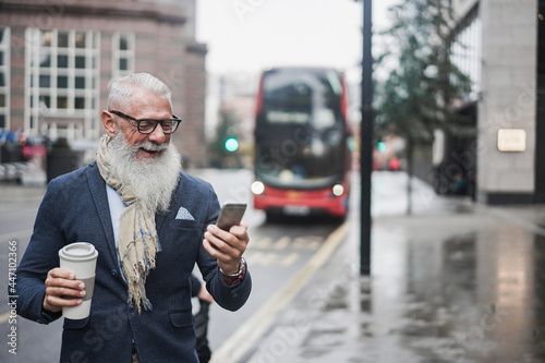 Canvas Print Senior business man going to work drinking coffee with london bus station in bac