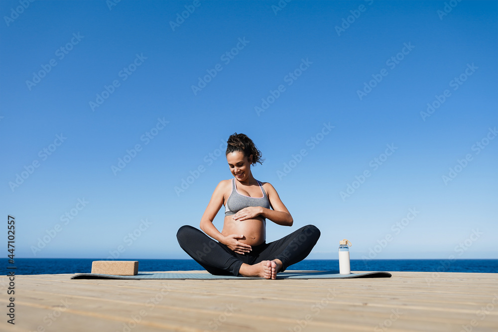 Fototapeta premium Young pregnant woman doing yoga outdoor - Focus on face