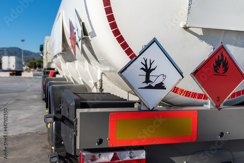 Tank truck with dangerous goods, with labels of flammable and pollutant of the environment. photo