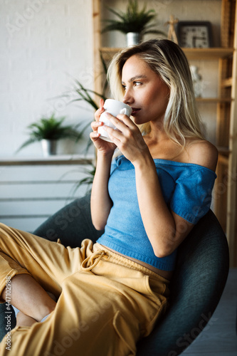 Attractive young woman drinking tea, coffee at home