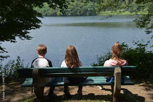 Kinder auf einer Parkbank schauen auf einen See