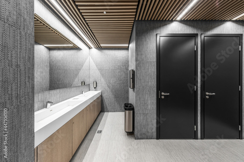 Fototapet Interior of a modern public restroom with wood and grey clay elements and black