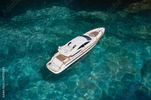 Super yacht on clear water near the rocks, top view. A huge white super Mega yacht on blue water in Italy.