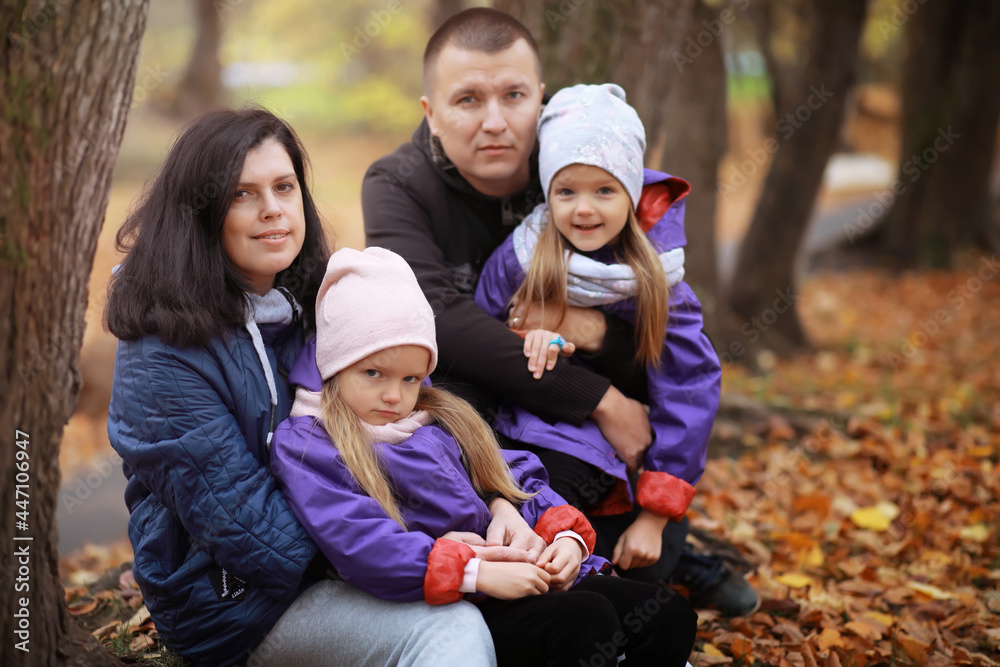 Young family on a walk in the autumn park on a sunny day. Happiness to be together.