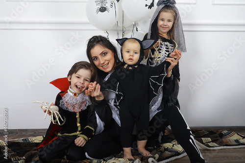 Happy family with children in costumes of witch and vampire in a house in holiday Halloween