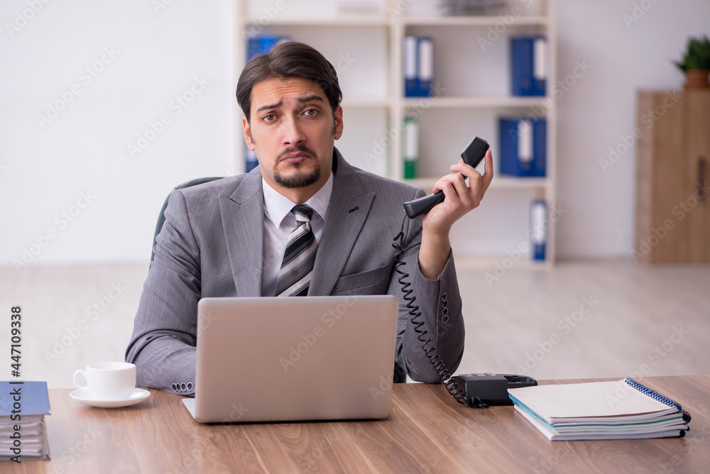 Young attractive male employee sitting at workplace Young attractive male employee sitting at workplace