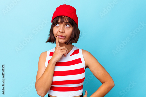 Young mixed race woman isolated on blue background contemplating, planning a strategy, thinking about the way of a business.