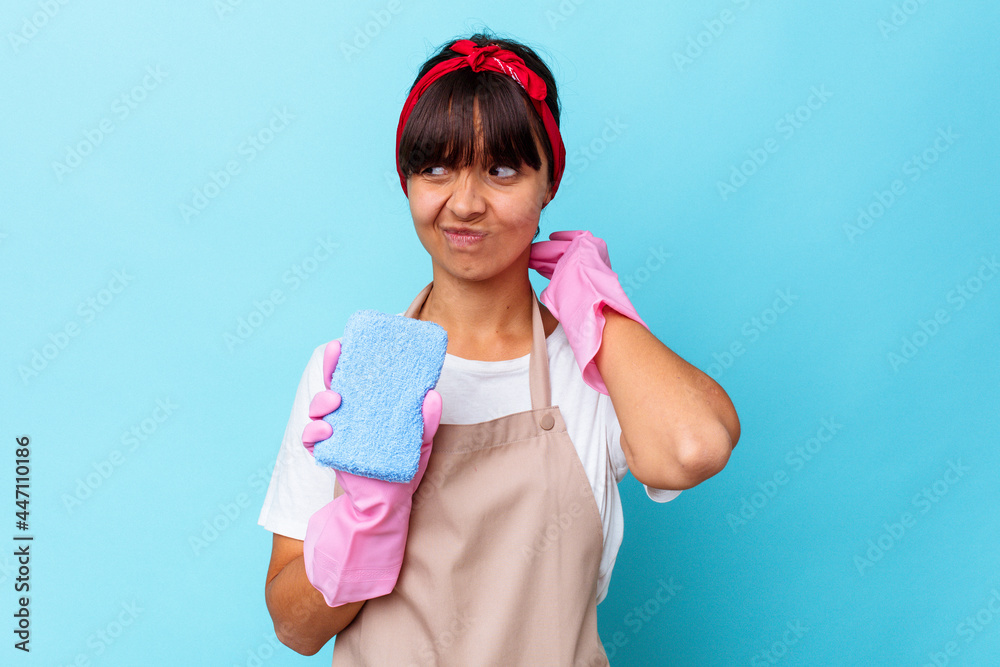 Young mixed race woman cleaning home isolated on blue background touching back of head, thinking and making a choice. Young mixed race woman cleaning home isolated on blue background touching back of head, thinking and making a choice.