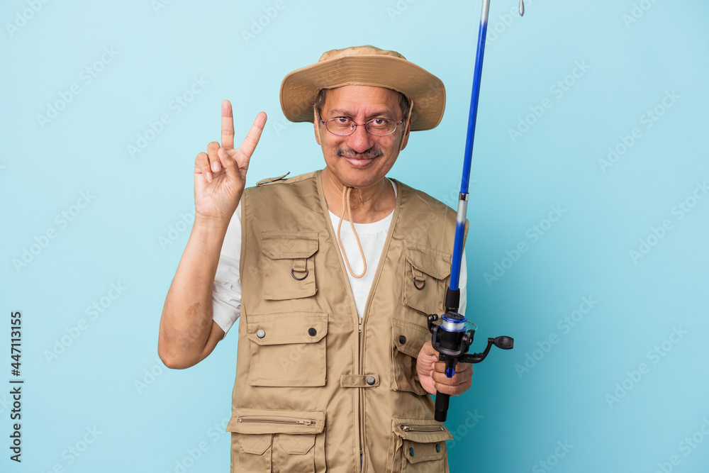 Senior indian fisherman holding rod isolated on blue background showing number two with fingers. Senior indian fisherman holding rod isolated on blue background showing number two with fingers.