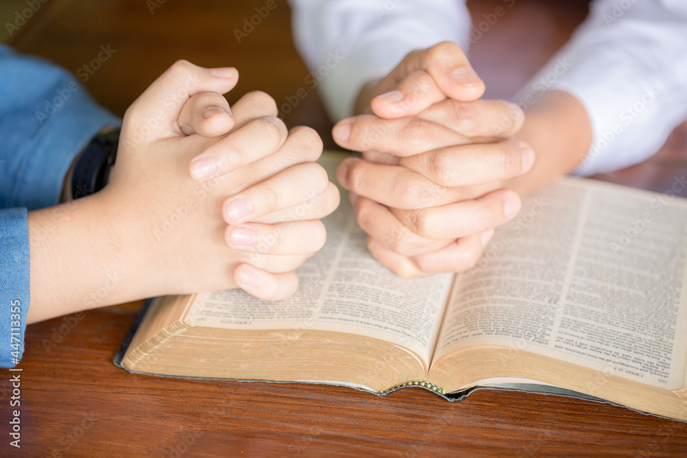 Hands folded in prayer on a Holy Bible Hands folded in prayer on a Holy Bible