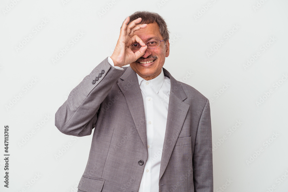 Middle aged indian business man isolated on white background excited keeping ok gesture on eye. Middle aged indian business man isolated on white background excited keeping ok gesture on eye.