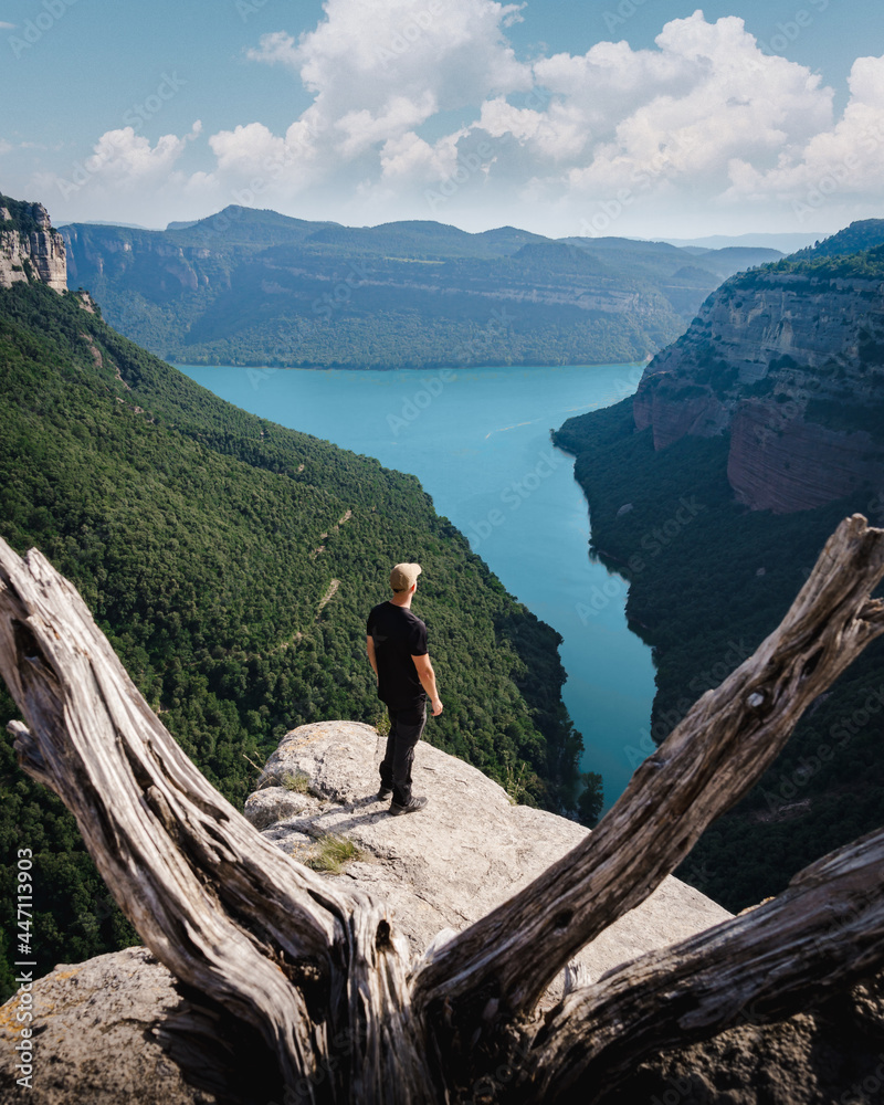 man looking at a lake on the top of a rock