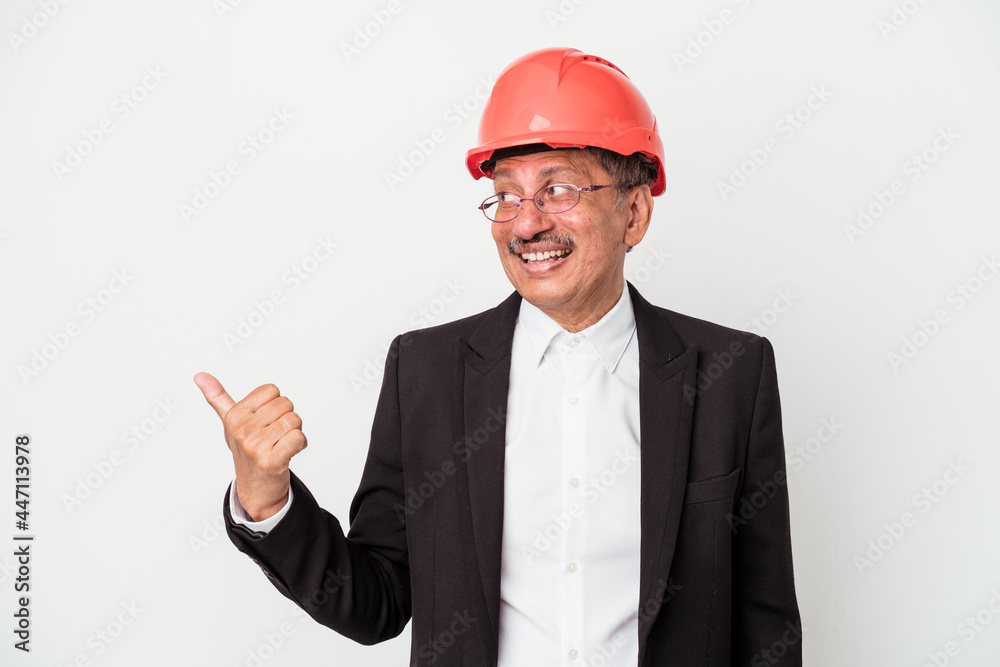 Middle aged indian architect man isolated on white background points with thumb finger away, laughing and carefree. Middle aged indian architect man isolated on white background points with thumb finger away, laughing and carefree.
