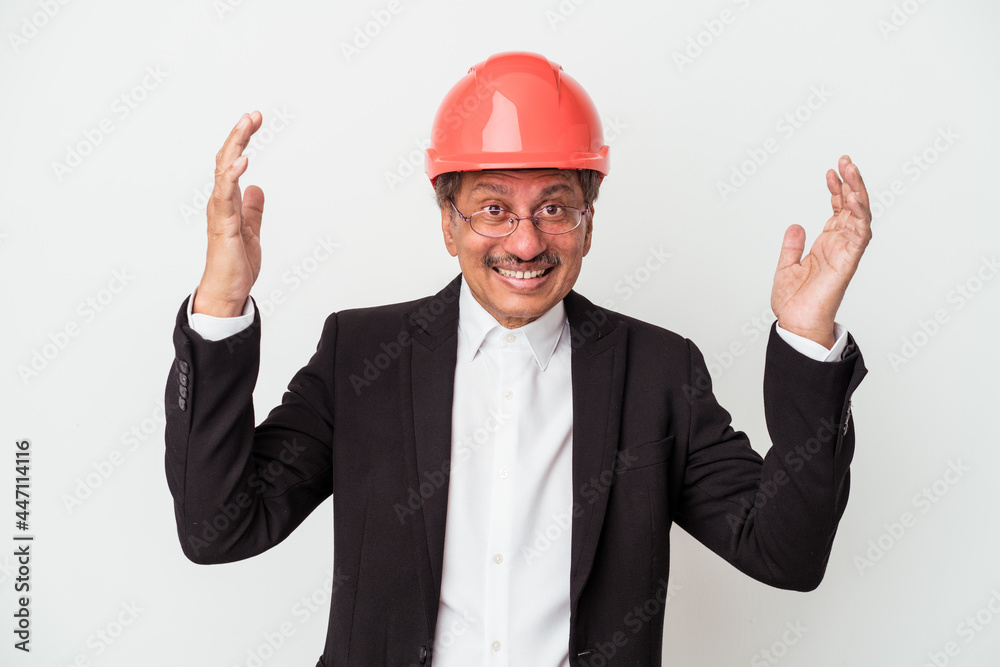 Middle aged indian architect man isolated on white background receiving a pleasant surprise, excited and raising hands. Middle aged indian architect man isolated on white background receiving a pleasant surprise, excited and raising hands.