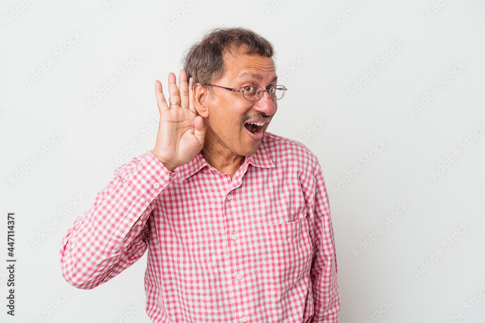 Middle aged indian man isolated on white background trying to listening a gossip. Middle aged indian man isolated on white background trying to listening a gossip.