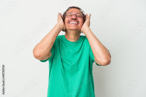 Middle aged indian man isolated on white background laughs joyfully keeping hands on head. Happiness concept.