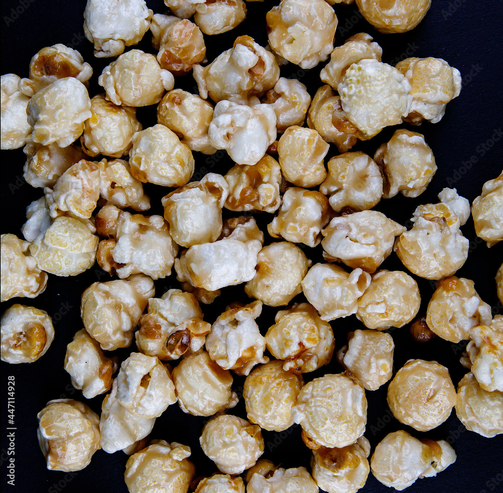 Crispy popcorn on a black background. Popcorn in caramel glaze. Crispy popcorn on a black background. Popcorn in caramel glaze.