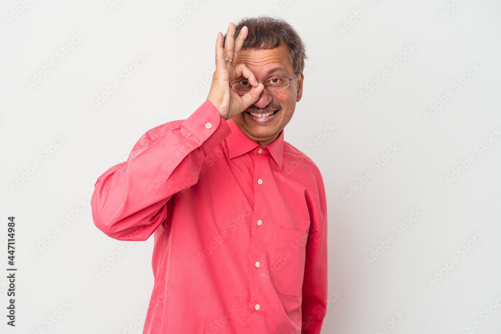 Middle aged indian man isolated on white background excited keeping ok gesture on eye. Middle aged indian man isolated on white background excited keeping ok gesture on eye.