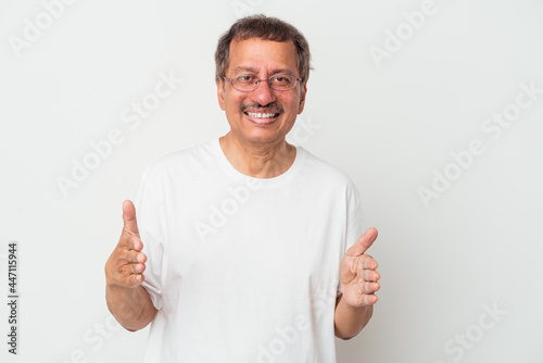 Middle aged indian man isolated on white background holding something with both hands, product presentation.