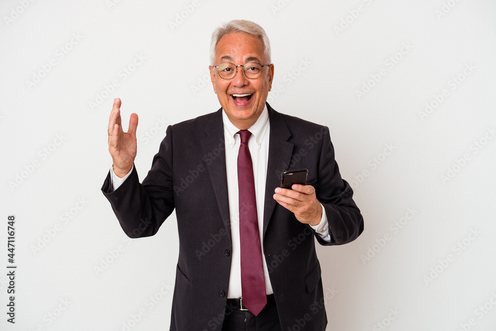 Senior business american man holding mobile phone isolated on white background receiving a pleasant surprise, excited and raising hands. Senior business american man holding mobile phone isolated on white background receiving a pleasant surprise, excited and raising hands.