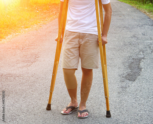 The picture shows patients with ankle injuries with bandages ankle brace and use crutches to support walking on the lawn. Healthcare and medical concept.