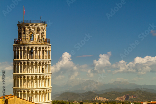The leaning Tower of Pisa across the rooftops with the mountains in the distance