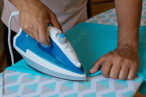 Unrecognizable man ironing clothes in his bedroom 