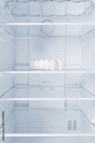chicken eggs in a tray, in the refrigerator on a glass shelf, on a white background
