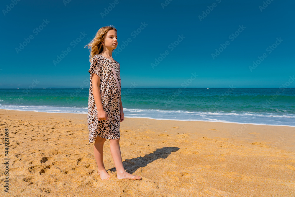 Young beautiful girl in beige dress staying along the sandy beach near the waves. High quality photo Young beautiful girl in beige dress staying along the sandy beach near the waves. High quality photo