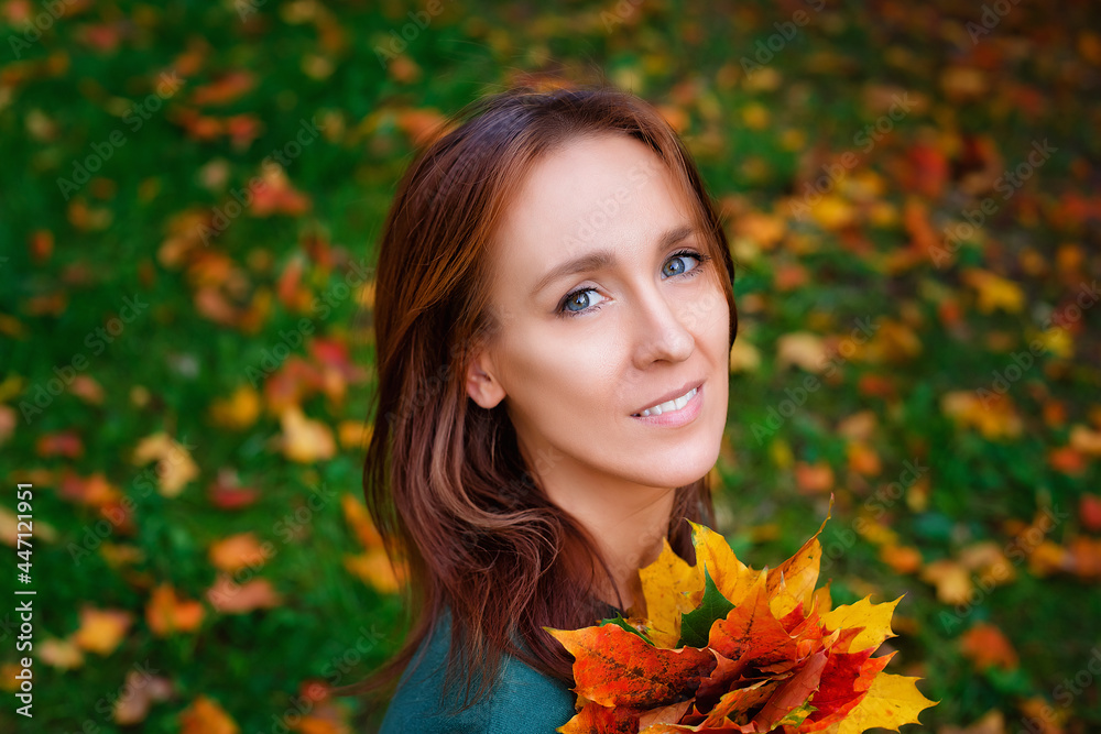 A beautiful young woman with a bouquet of yellow-red maple leaves in the park against the background of fallen foliage. A beautiful young woman with a bouquet of yellow-red maple leaves in the park against the background of fallen foliage.