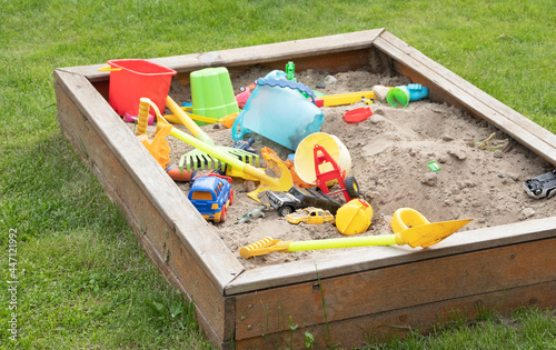 children's sandbox with toys on green grass