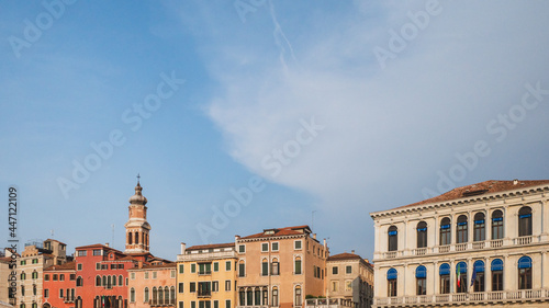 Tower over colorful Venetian houses under blue sky, Venice, Italy