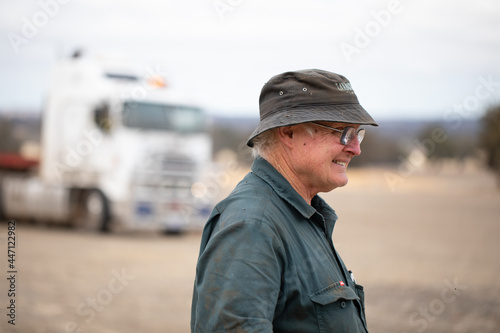 older man in workwear outdoors with prime mover in background photo