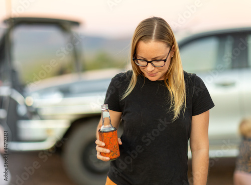 lady with beer in hand and blurry vehicle in background photo