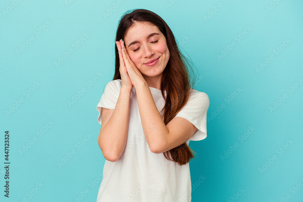 Young caucasian woman isolated on blue background yawning showing a tired gesture covering mouth with hand. Young caucasian woman isolated on blue background yawning showing a tired gesture covering mouth with hand.