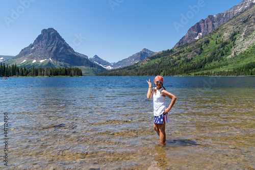 Woman wearing American flag patriotic clothing gives a peace sign at Two Medicine Lake in Glacier National Park photo
