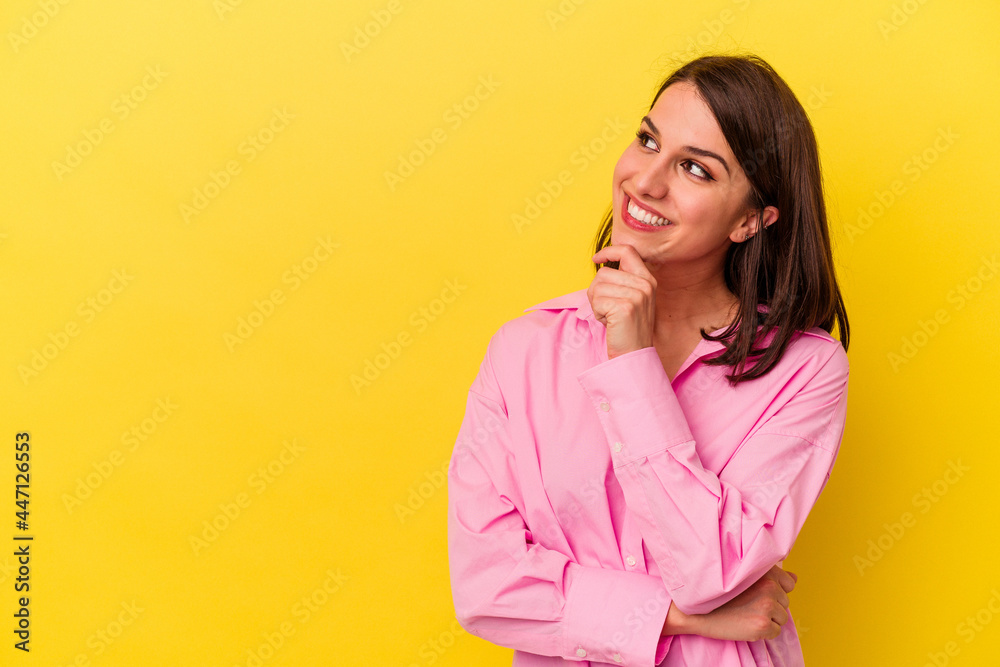 Young caucasian woman isolated on yellow background relaxed thinking about something looking at a copy space.