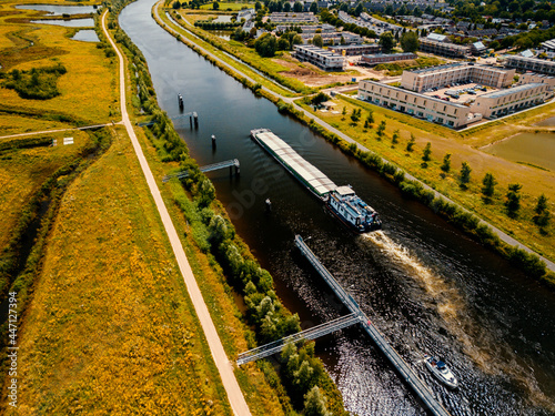 Fotografie Aerial drone view of the big container shipping boat at the canal in the Netherl