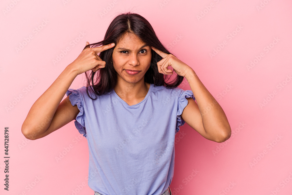 Young latin woman isolated on pink background focused on a task, keeping forefingers pointing head. Young latin woman isolated on pink background focused on a task, keeping forefingers pointing head.