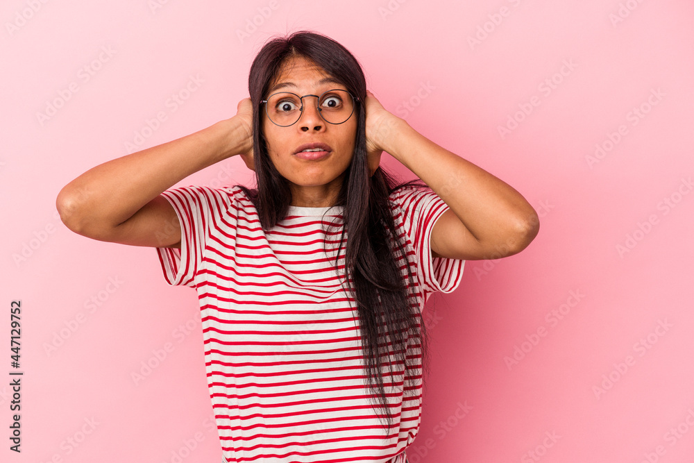Young latin woman isolated on pink background covering ears with hands trying not to hear too loud sound. Young latin woman isolated on pink background covering ears with hands trying not to hear too loud sound.