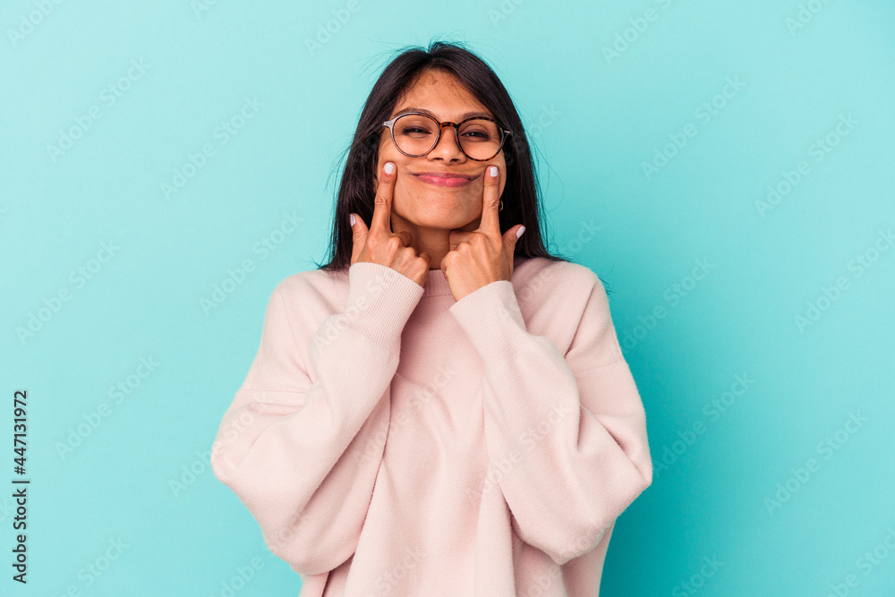 Young latin woman isolated on blue background doubting between two options. Young latin woman isolated on blue background doubting between two options.