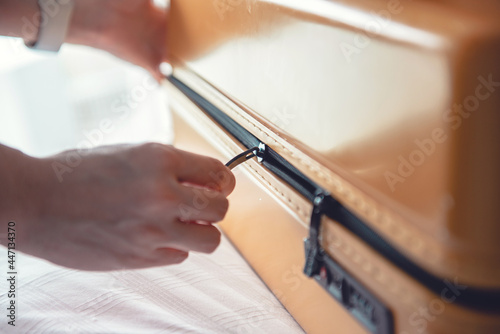 Fotografie, Obraz Close up of hands zipping a travel suitcase luggage bag on bed in bedroom