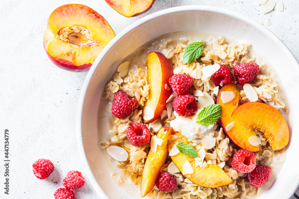 Summer oatmeal with raspberries, peaches and nuts. Healthy vegetarian food concept. Summer oatmeal with raspberries, peaches and nuts. Healthy vegetarian food concept.