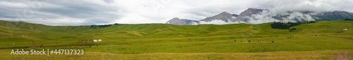 Panoramic view of summer pastures in Kegen region of Kazakhstan. Rural life with traditional yurts houses.