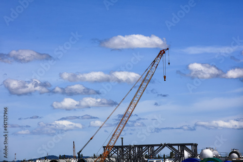Power crain at site line aginst blue cloudly sky on sunny day photo