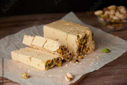 Organic halva with pistachios on a wooden surface. Traditional middle eastern sweets. Jewish, turkish, arabic oriental national dessert. Turkish delight concept. Natural vegan product. Copy space.