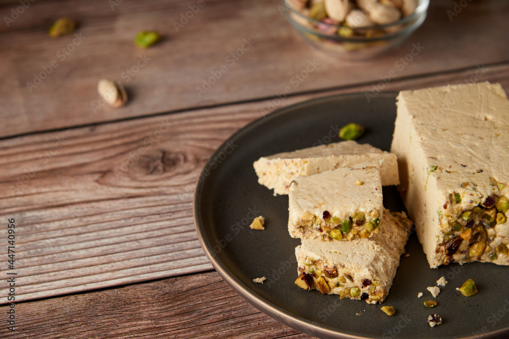 Organic halva with pistachios on a wooden surface. Traditional middle eastern sweets. Jewish, turkish, arabic oriental national dessert. Turkish delight concept. Natural vegan product. Copy space. Organic halva with pistachios on a wooden surface. Traditional middle eastern sweets. Jewish, turkish, arabic oriental national dessert. Turkish delight concept. Natural vegan product. Copy space.
