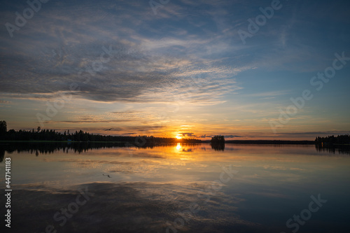 Tranquil golden hour cloud above the forest lake at sunset. Dramatic cloudscape. Symmetry reflections on the water  natural mirror.