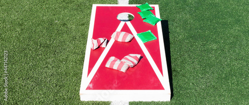 Cornhole board with eight bean bags on top on a turf field photo