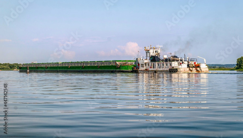 River barge and tugboat carrying cargo on the river